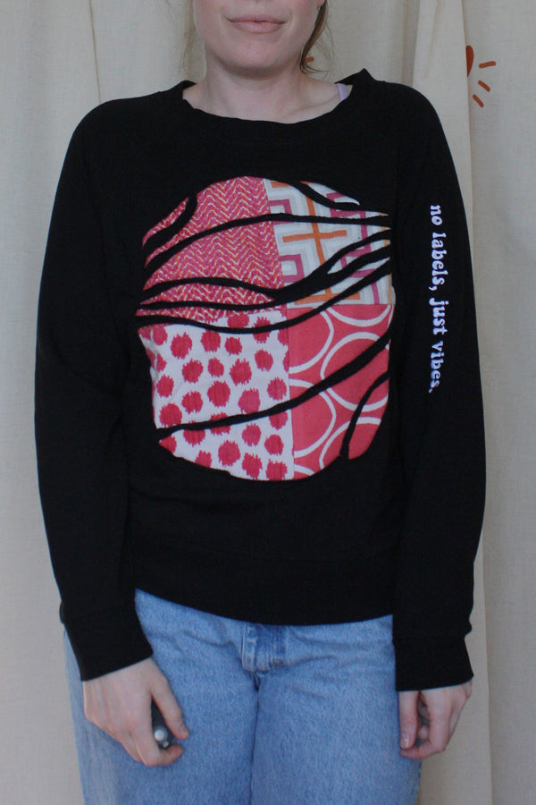 black upcycled sweater with hot pink and orange graphic fabric in the front, repurposed in canada