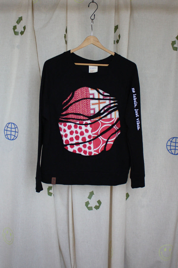 black upcycled sweater with hot pink and orange graphic fabric in the front, repurposed in canada