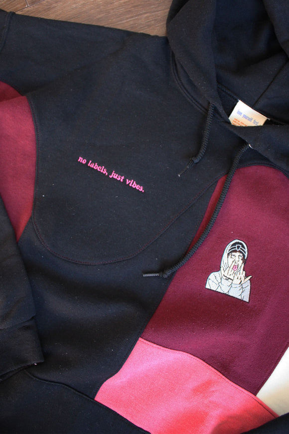 black upcycled hoodie, with patchwork design and pops of pink, cream and red, repurposed in canada, detail shot of 'no labels, just vibes.' embroidery