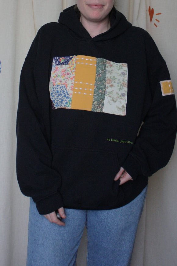 black upcycled hoodie with mustard and green quilt on the front, repurposed in canada