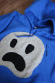 blue upcycled hoodie with fuzzy ghost face on front, repurposed in canada, detail shot of 'no labels, just vibes.' embroidery