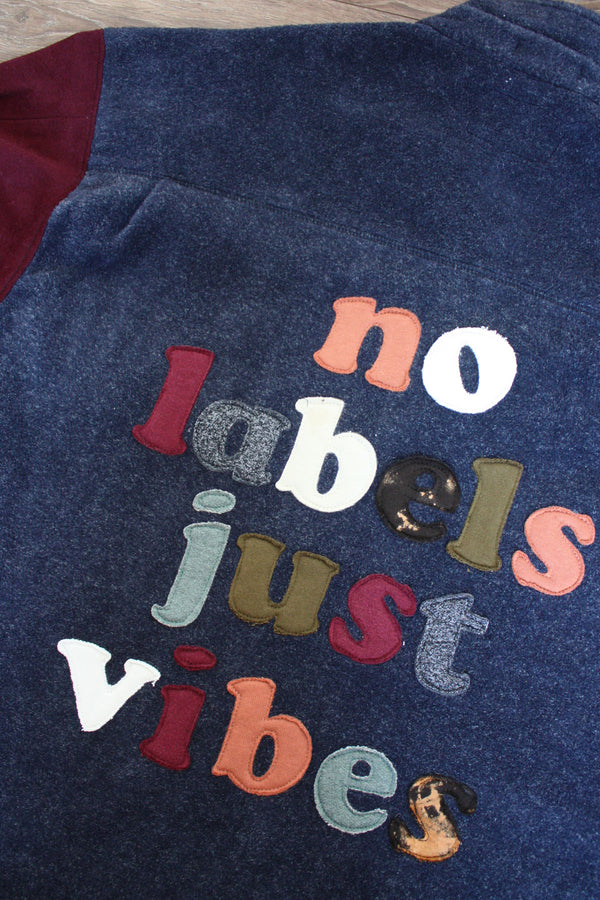 navy shacket with plum sleeves, and lettering on the back with our motto 'no labels, just vibes.' upcycled in canada