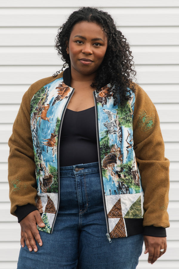 one of a kind bomber jacket that features canadian woodland scenes with a green, brown, and white quilted back. It also features brown wool sleeves with visible mending, repurposed in canada