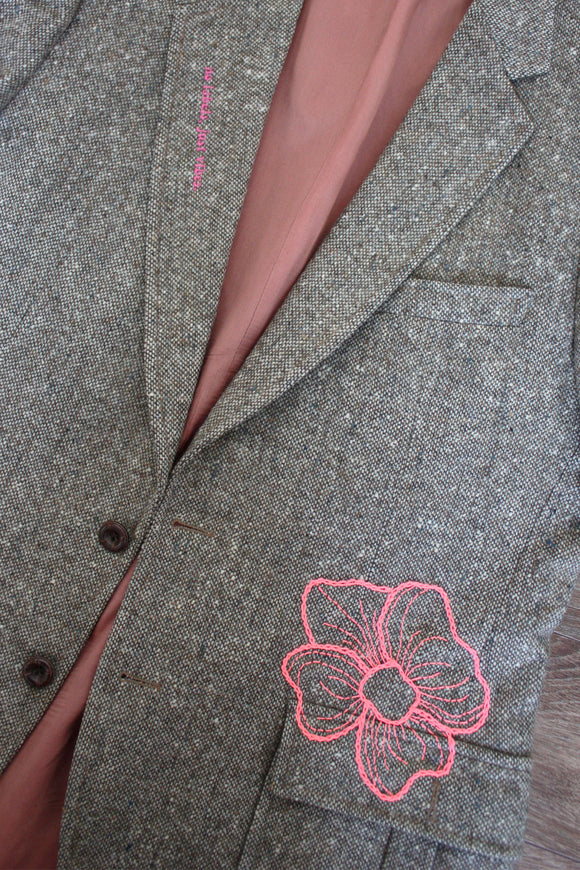 beige/brown upcycled blazer with pink hand embroidered flower, repurposed in canada, detail shot of embroidered peony and 'no labels, just vibes.' embroidery