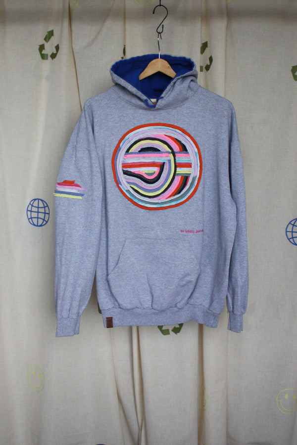 grey hoodie with colourful motif on front, sleeve and hoodie. this upcycled gem is one of a kind and uses sweater seams to bring this design to life. repurposed in canada