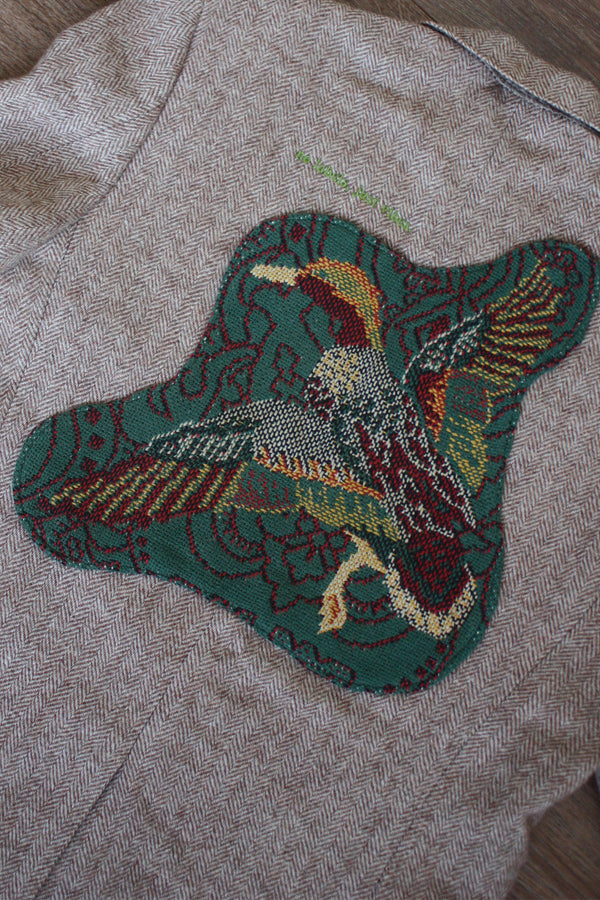 brown blazer with green plaid pockets, and green duck on the back, repurposed in canada detail shot of duck in flight on back blazer, and 'no labels, just vibes.' embroidery