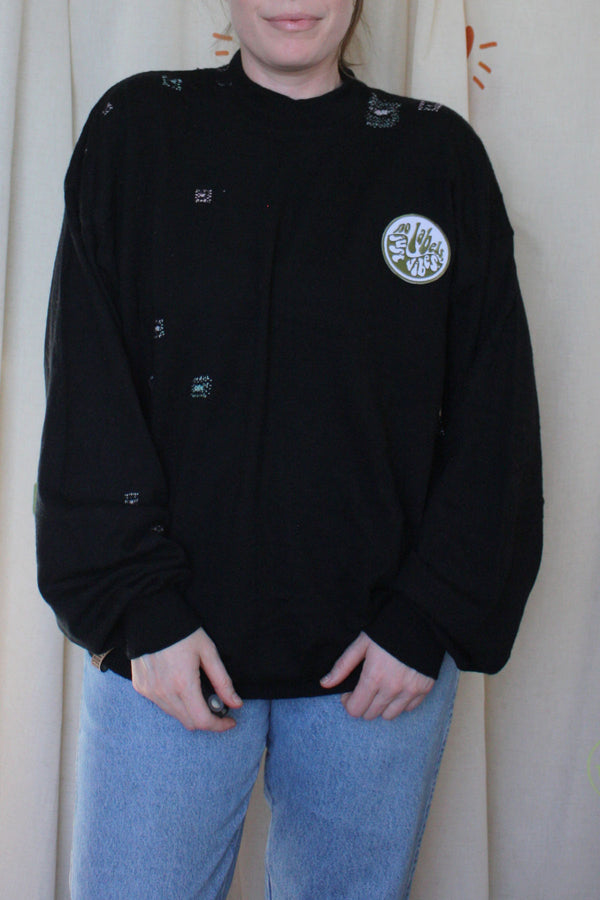 black knit jumper with visible mending and 'no labels, just vibes.' patch, upcycled in canada