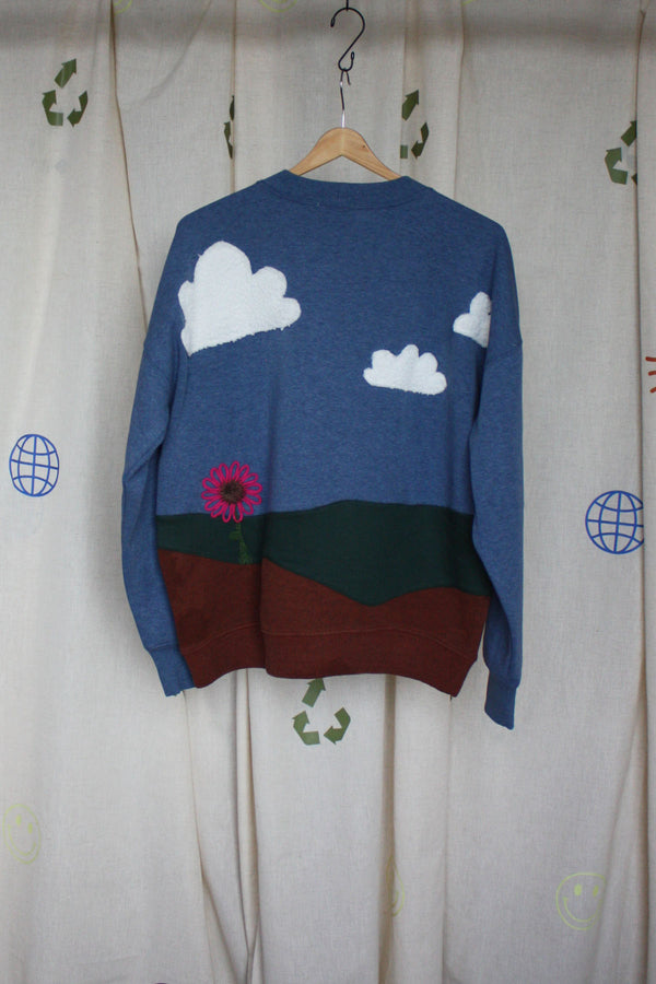 upcycled earth sweater featuring the earth, grass, sky with the sun, clouds  and a flower, repurposed in canada