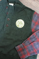 upcycled green knit sweater with red plaid sleeves, repurposed in canada, detail shot of 'no labels, just vibes.' patch