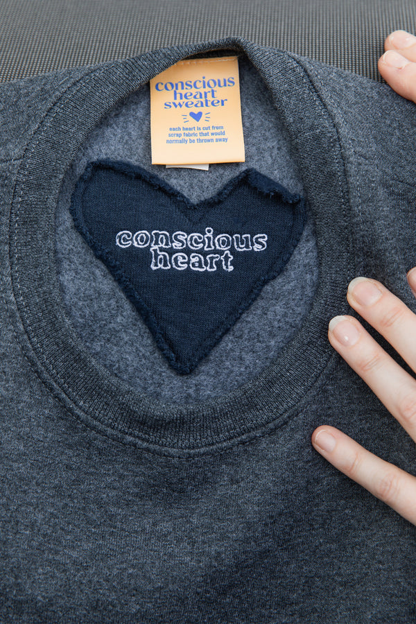 smaller 'conscious heart' stitched on back neck of charcoal sweater, sewn in canada