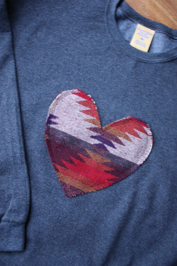 Indigenous woven heart sewn onto charcoal sweater, unisex and oversized fit, sewn in Canada