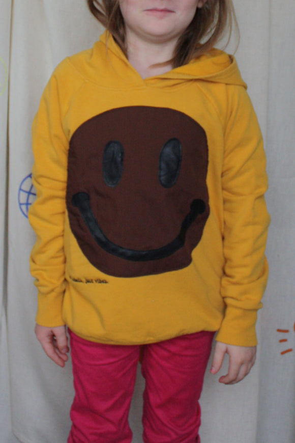 yellow upcycled hoodie worn by 6 year old, brown smiley face repurposed in canada