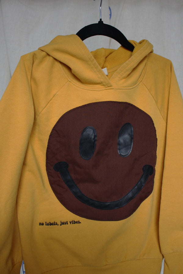 yellow upcycled hoodie worn by 6 year old, brown smiley face repurposed in canada