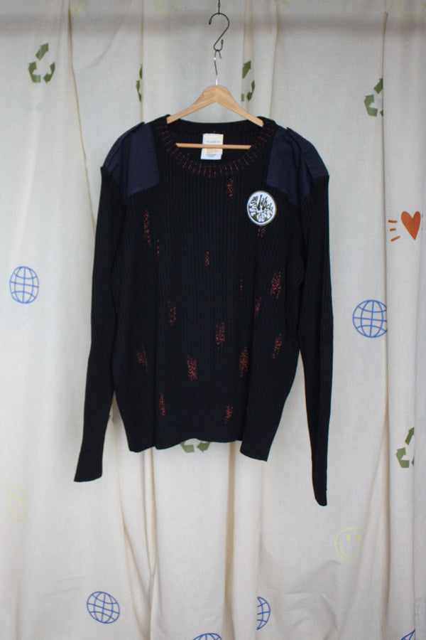 black upcycled knit sweater with visible mending, a 'no labels, just vibes' patch and floral elbow patches