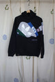 black hoodie featuring lots of colourful logos from big brands, upcycled in canada