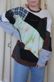 green, orange tie-dyed, cream, red plaid, blue plaid and black patchwork sweater. Made using scrap fabric and upcycled in canada