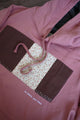 pink hoodie with brown quilting on the front with tiny pink flowers, upcycled in canada, detail shot of 'no labels, just vibes.' embroidery 