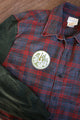 red plaid shirt upcycled with green sleeves, repurposed in canada, detail shot of 'no labels, just vibes.' patch