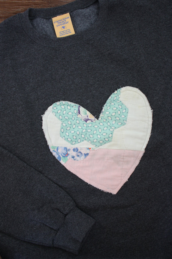 one of a kind quilted heart stitched on a charcoal sweater, unisex and oversized fit, hand cut and sewn in canada