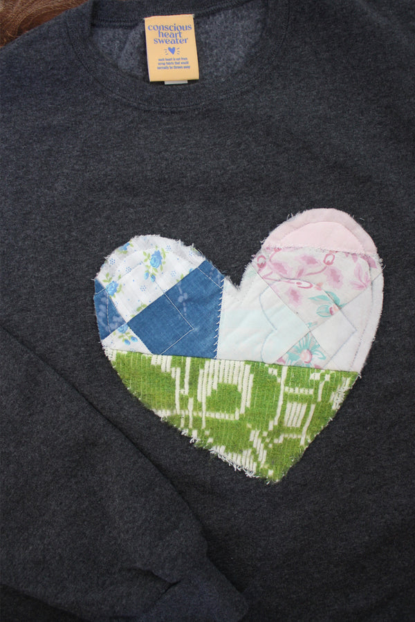 one of a kind quilted heart stitched on a charcoal sweater, unisex and oversized fit, hand cut and sewn in canada