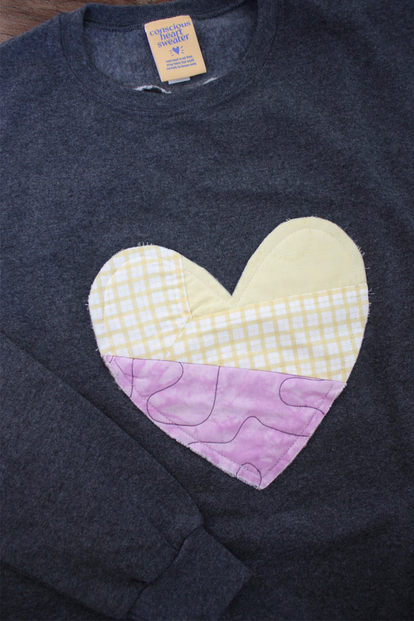 one of a kind quilted heart stitched on a charcoal sweater, unisex and oversized fit, hand cut and sewn in canada