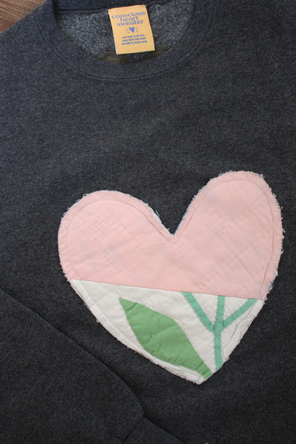 one of a kind quilted heart stitched on a charcoal sweater, unisex and oversized fit, hand cut and sewn in canada