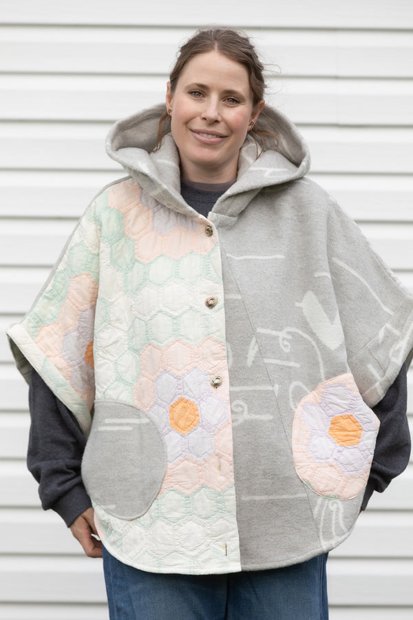 oversized upcycled quilt poncho with hood and pockets. pastel pink, green purple and orange and grey blanket material, repurposed in canada