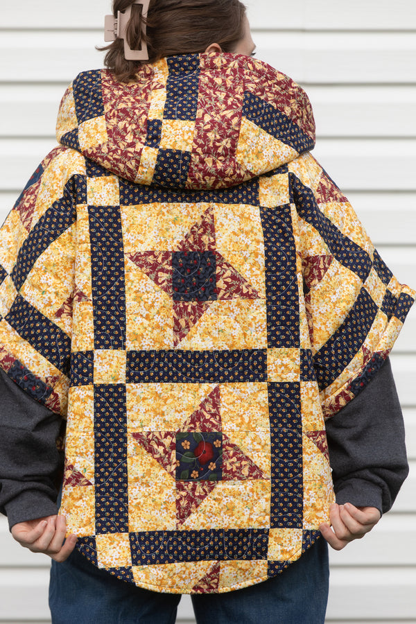 fall harvest quilt repurposed into poncho, featuring cozy hood and pockets that are lined with navy wool. made in canada