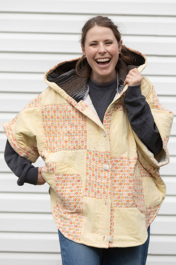 oversized upcycled quilted poncho with big hood and pockets. made from yellow and orange quilt with colourful daisies, made in canada