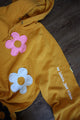 yellow upcycled hoodie with colourful flowers all over, repurposed in canada, detail shot of 'no labels, just vibes.' embroidery